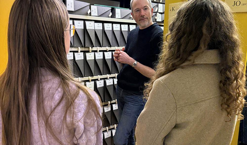 Apolline et Elisa pénètrent maintenant dans les magasins, ces grandes pièces meublées d’immenses rayonnages où « dorment » toutes sortes de documents d’archives : registres paroissiaux, actes d’état civil, cadastres, documents administratifs, actes de notaires… © Virginie Le Pape